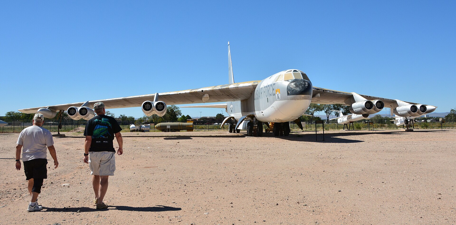 A retired B-52 Stratofortress on the desert apron of Heritage Park, with visitors walking toward it