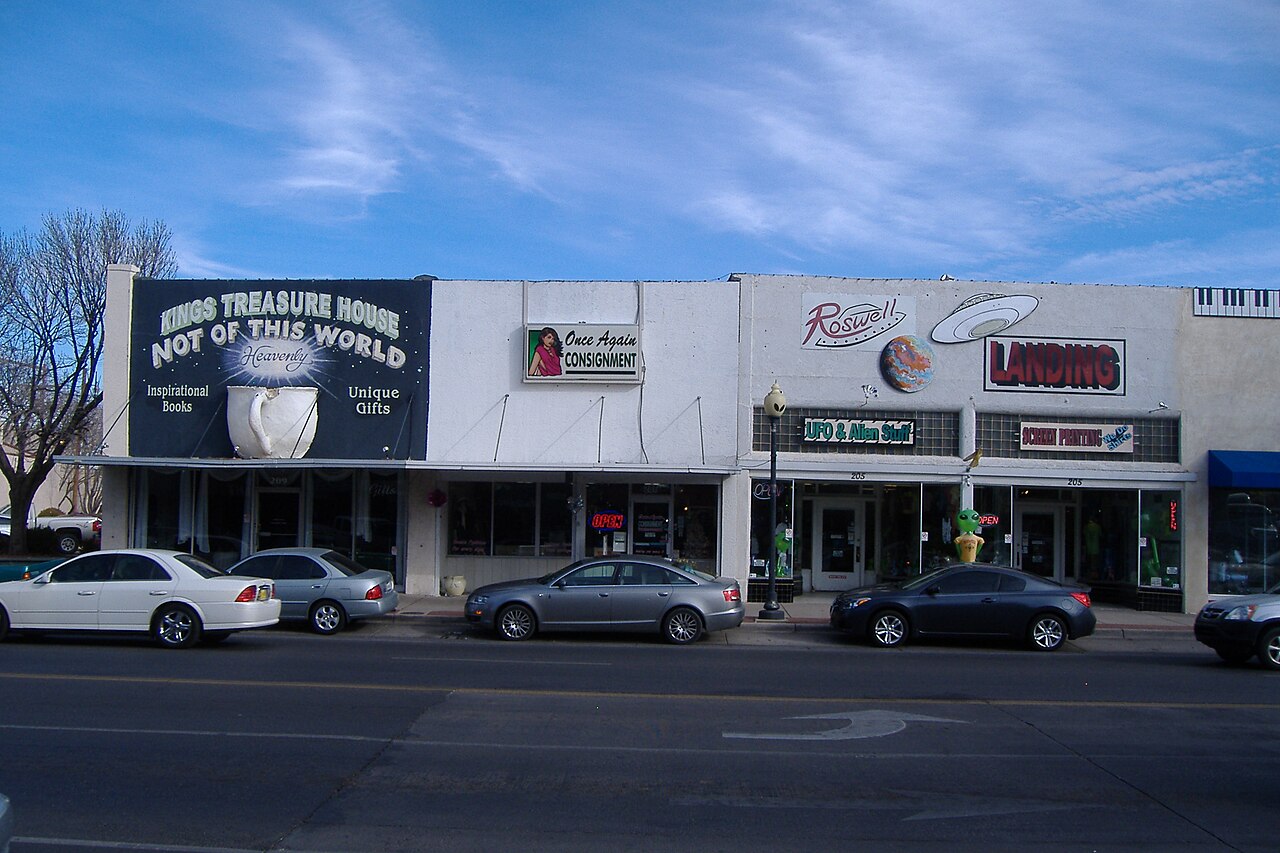 Main Street storefronts advertising UFO and alien merchandise, with alien statues in a doorway